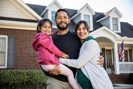 Happy family standing in front of a house